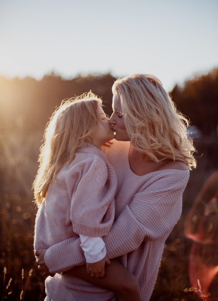 Eine Frau und ihre Tochter küssen sich in der Sonne.