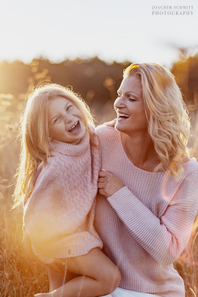 Eine Frau und ihre Tochter lachen auf einem Feld.