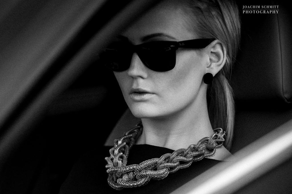 Eine Frau, die eine Sonnenbrille und eine Halskette in einem Auto trägt.